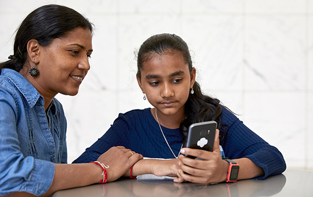 adult volunteer and girl scout sitting at table looking on phone at digital resources